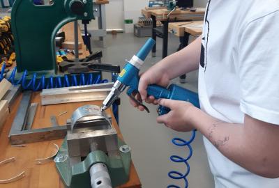 16.	Nýtování pneumatickou nýtovačkou při výrobě hliníkového dinosaura